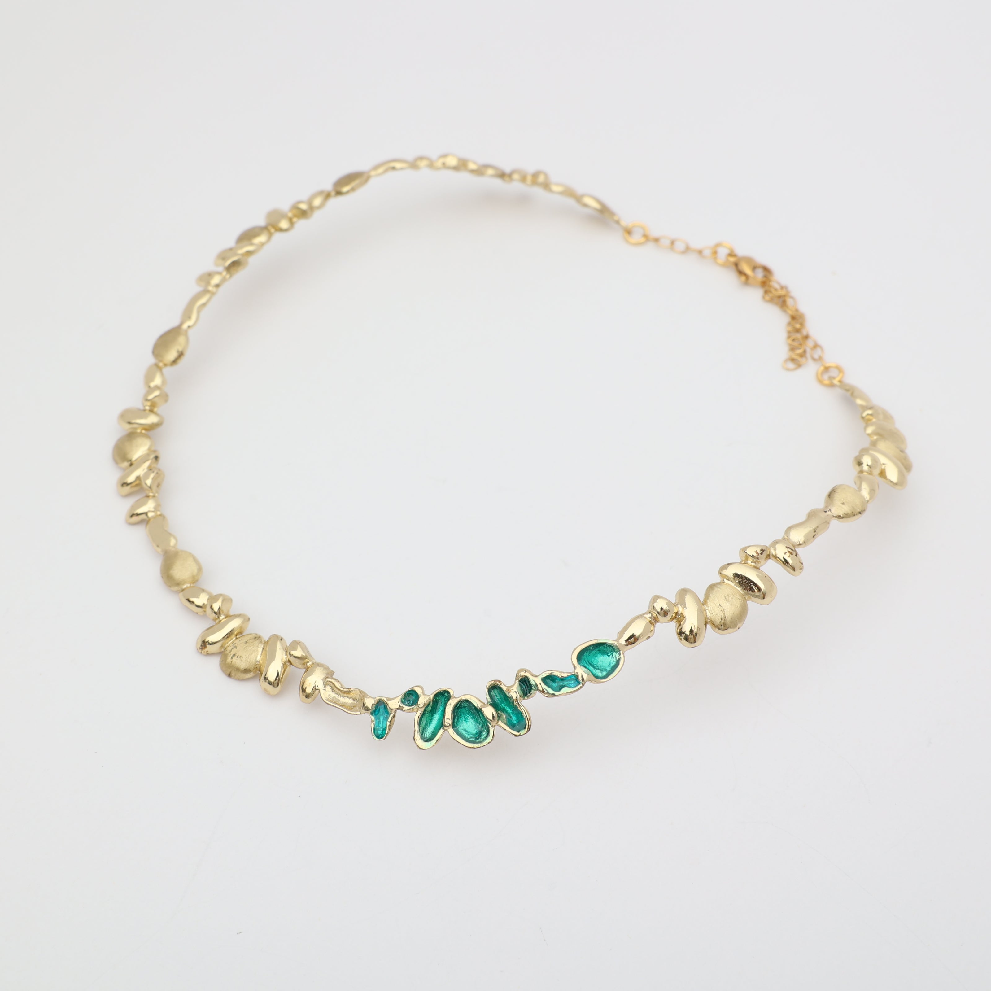 Gold necklace with green gemstones on a white background