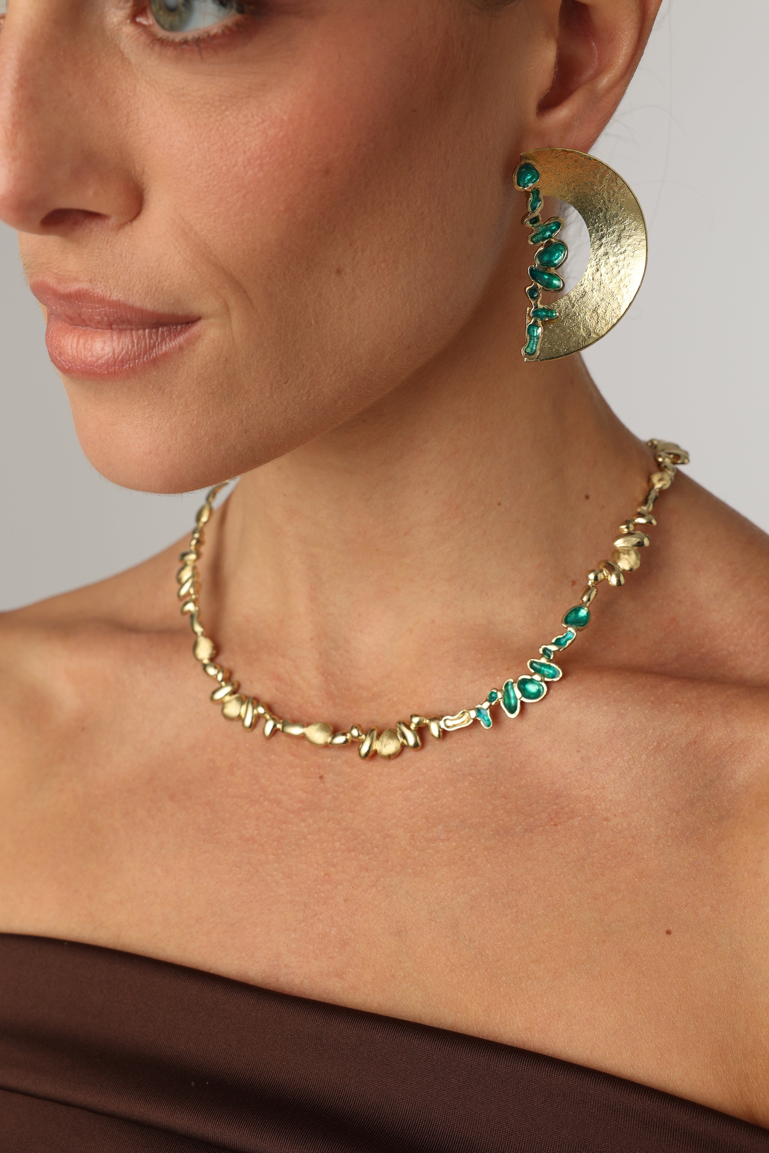 Gold-tone handmade brass necklace with organic molten texture and green enamel accents, crafted in Greece.
