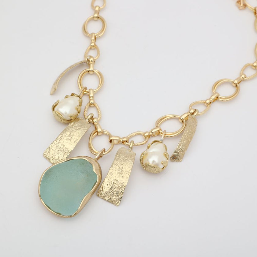 handmade brass charm necklace with pearl and stone pendants, flat lay view variant one