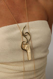 handmade brass long pendant necklace with Greek column and wave motif, close-up on model
