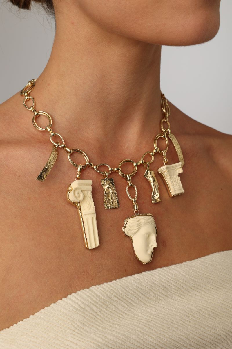 handmade brass charm necklace with ancient Greek sculptural pendants on model, close-up view