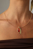 Handmade brass wire collar necklace with sculptural stone and leaf motif, close-up on neck
