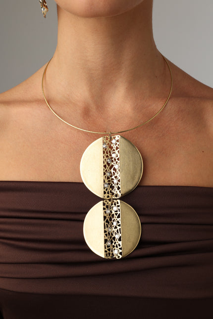 Model wearing a handmade Greek brass geometric set with crystals, including large drop earrings and a statement pendant necklace.