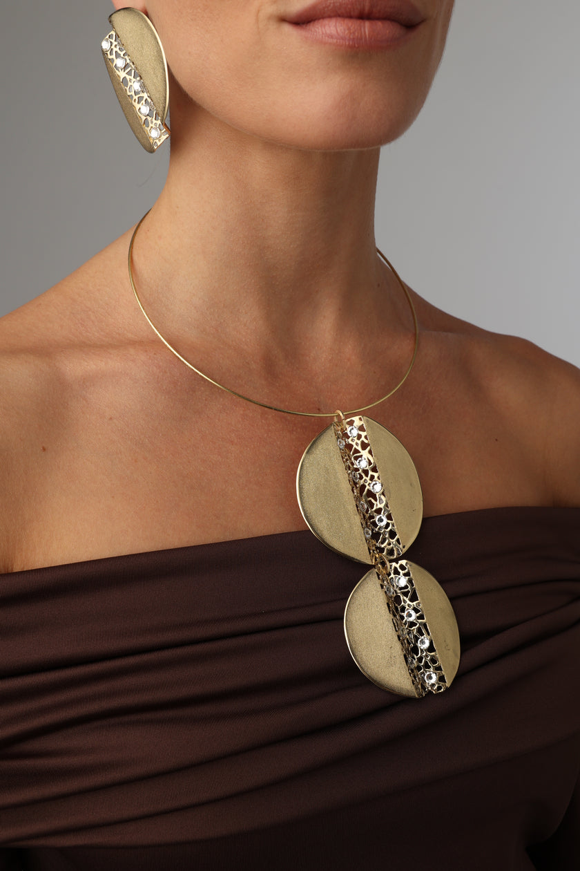 Gold arm cuffs with circular designs worn by a person against a neutral background