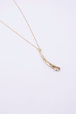 Glade handmade gold-plated brass pendant necklace with curved leaf-like pendant and clear baguette-cut crystal on a white background
