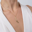 Woman wearing the Glade gold-plated pendant necklace with a textured leaf-shaped drop and baguette crystal on a fine gold chain, Savage Flora