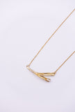 Pixie handmade gold-plated brass pendant necklace with crossed textured leaves and clear baguette-cut crystal on a white background