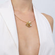 Brass flower and pearl pendant necklace worn with white top
