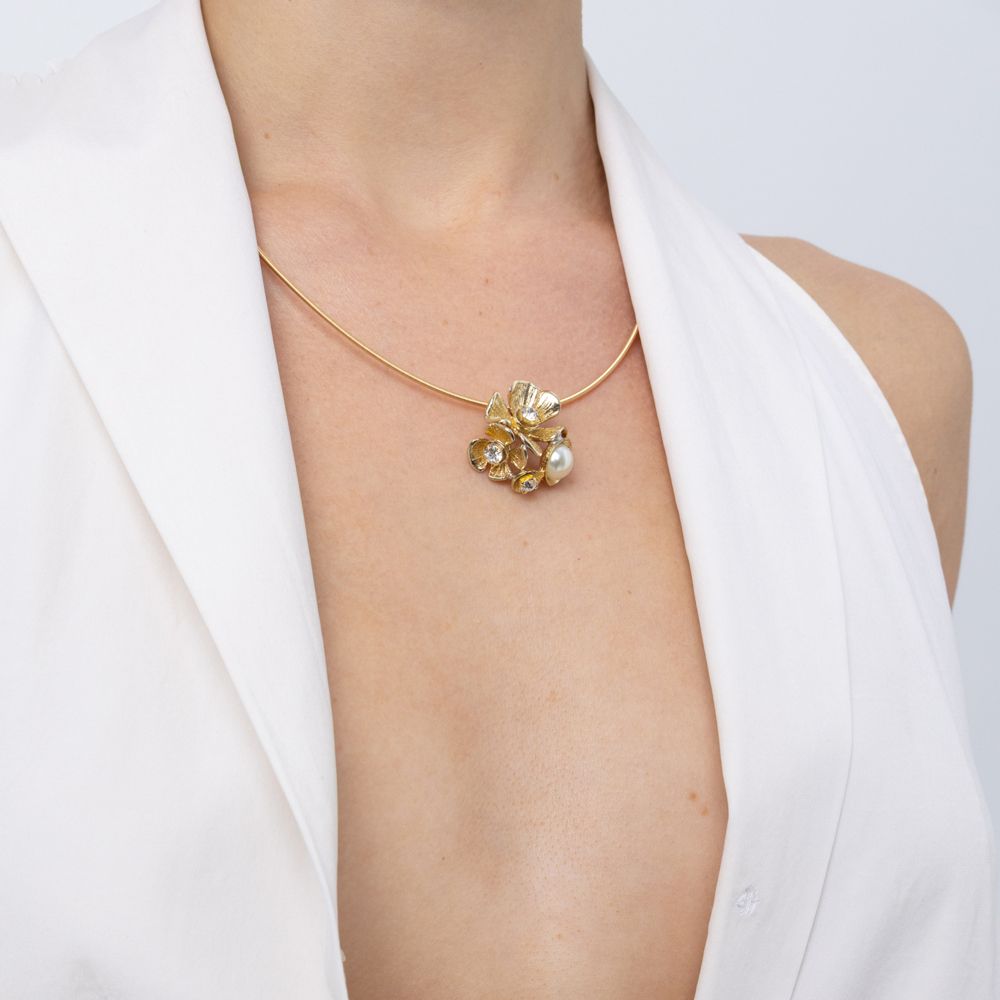 Brass flower and pearl pendant necklace worn with white top