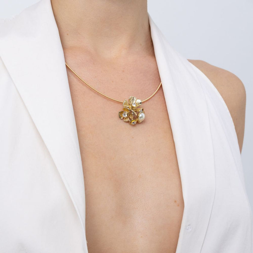 Brass flower and pearl pendant necklace worn with white top