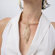 Model wearing the Pine gold statement necklace with textured needle-like pendant on a rigid gold collar, Savage Flora