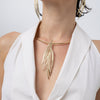 Model wearing the Pine gold statement necklace with textured needle-like pendant on a rigid gold collar, Savage Flora