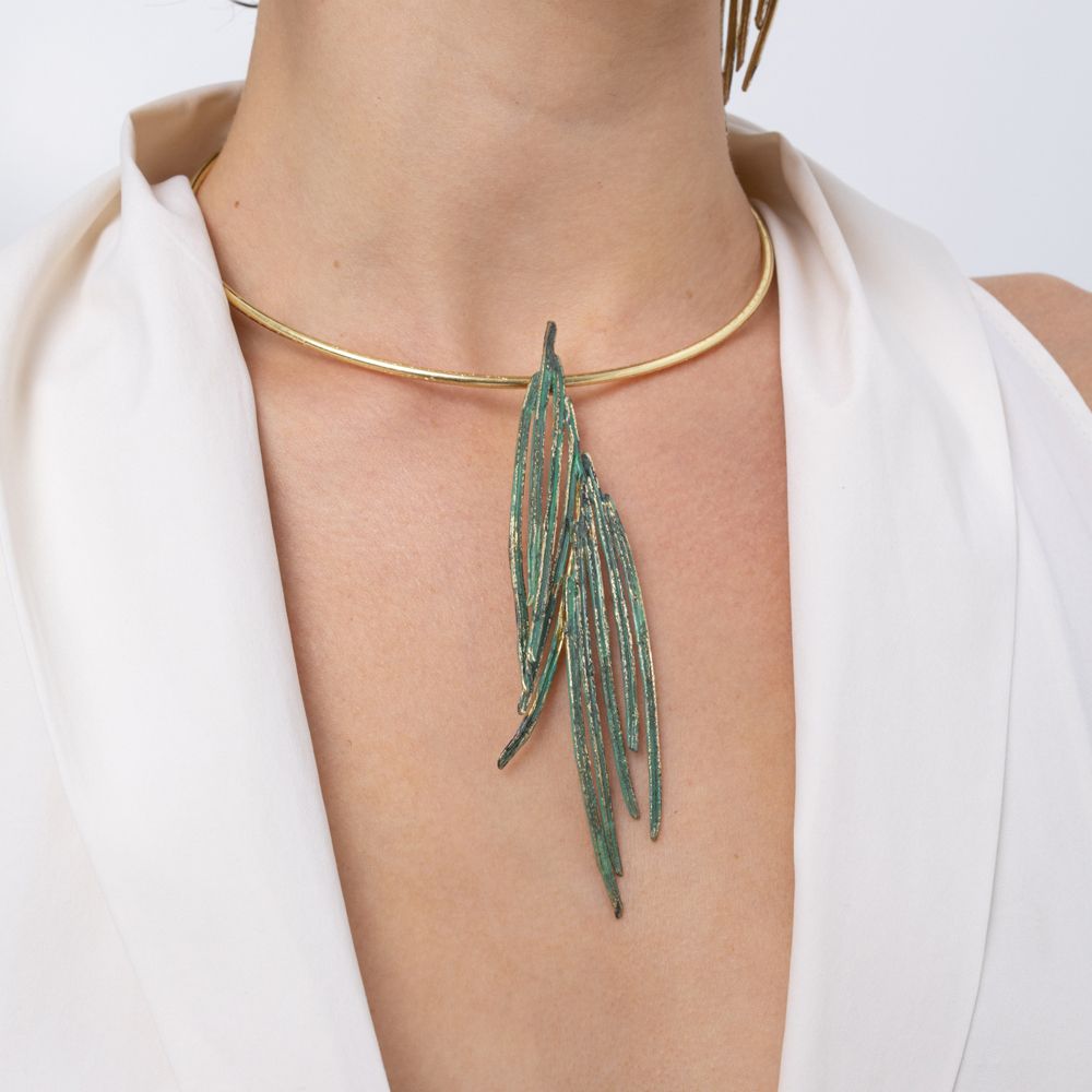 Woman wearing the Pine choker necklace with green patina pendant of layered pine-needle blades on a gold collar, Savage Flora