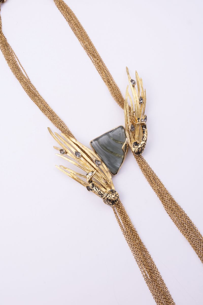 Double Peacock gold necklace with grey resin stone, black oxidized peacocks and crystal feather tips, detail view on white background