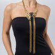 Woman wearing the Double Peacock gold-plated statement necklace with grey resin stone, crystal feathers and long gold tassel chains, Savage Flora