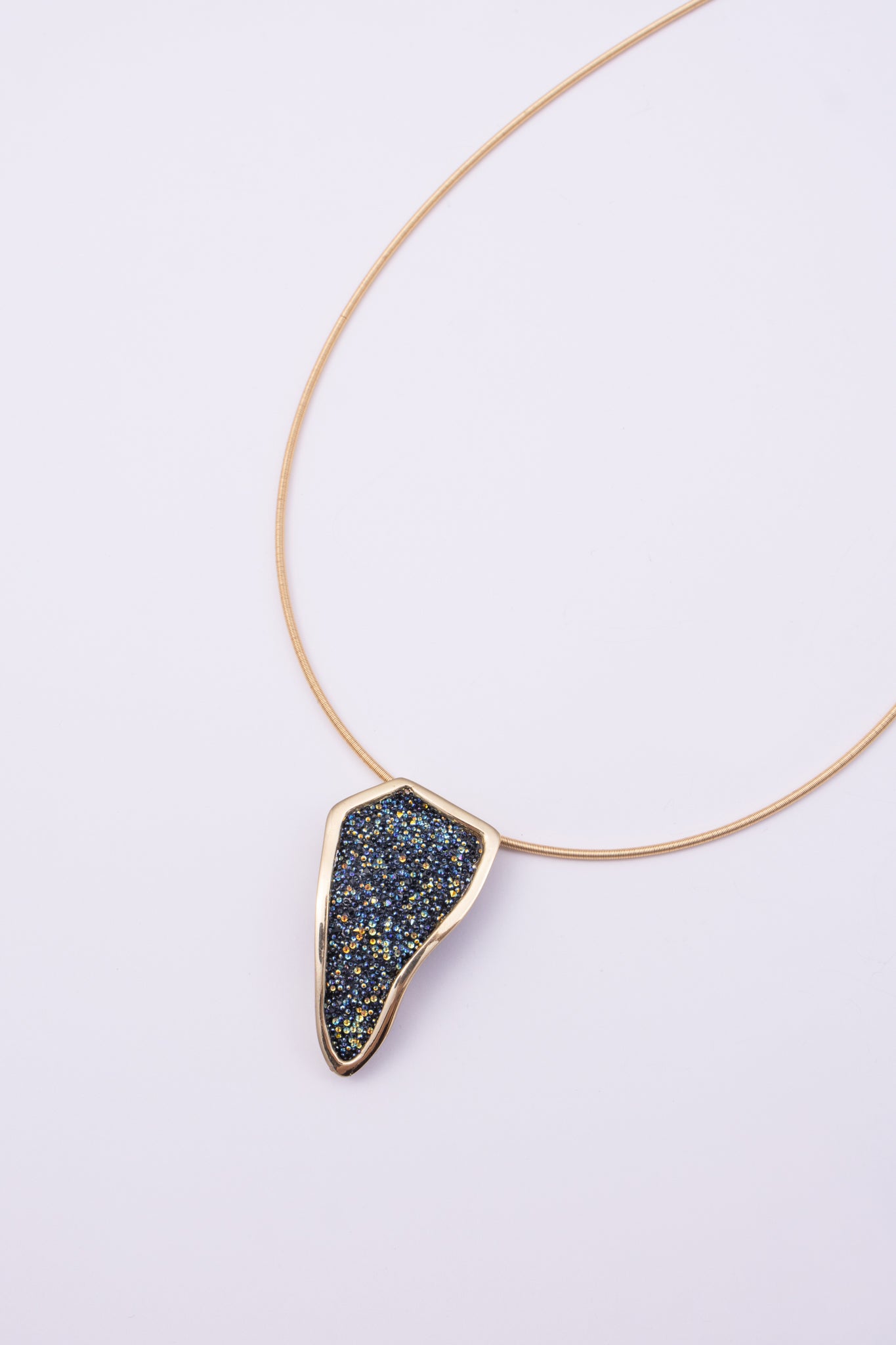 Edge Necklace on white background: handmade brass statement necklace with crystal pendant and slim coiled cord