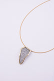 Edge Necklace close up: handmade brass pendant with tiny faceted crystals set in a sleek brass frame