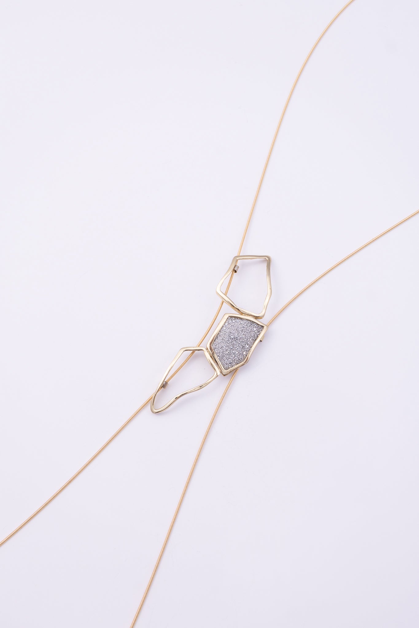 Glow Long Necklace close up: handmade brass pendant with tiny faceted crystals framed by open organic loops