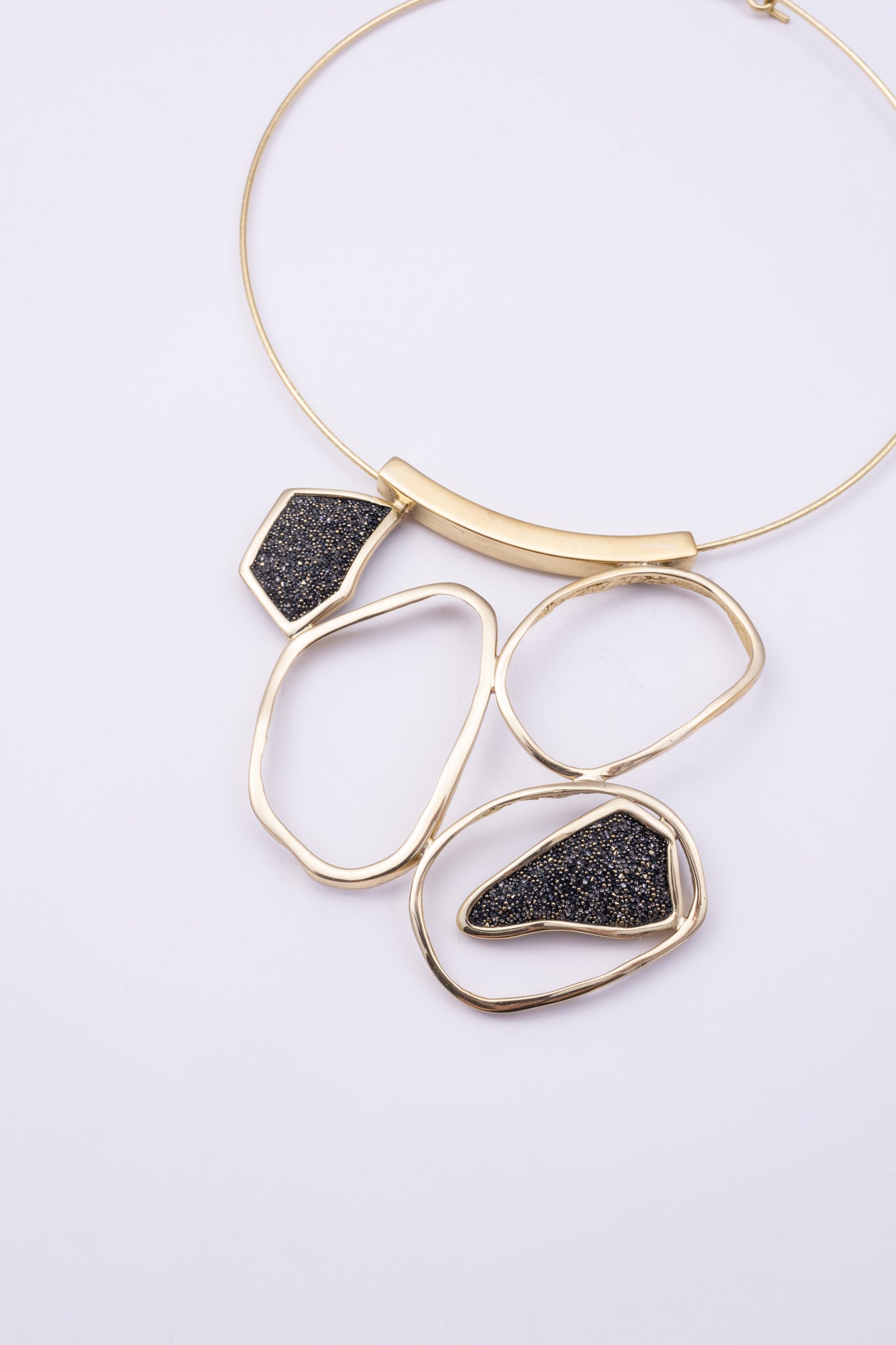 Glow Necklace close up: handmade brass necklace with tiny faceted crystals framed by sculpted brass loops