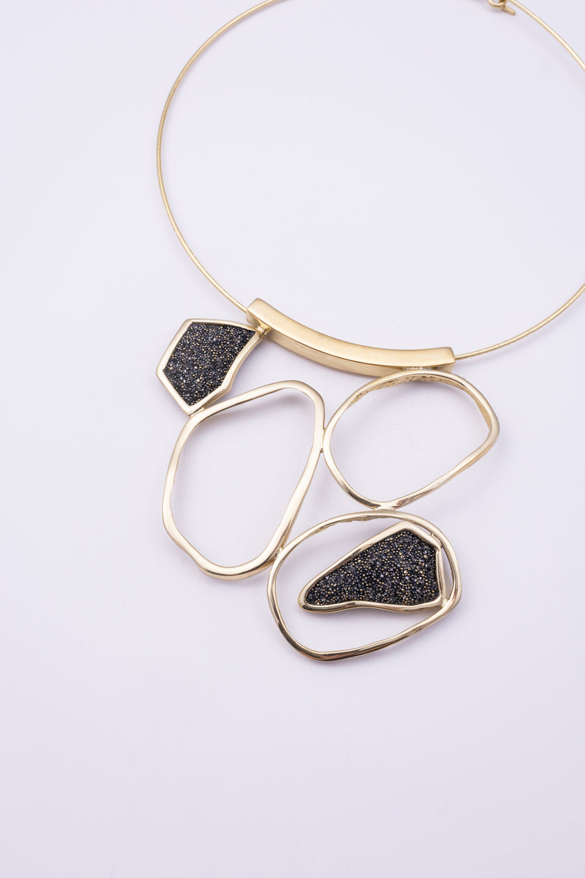 Glow Necklace close up: handmade brass necklace with tiny faceted crystals framed by sculpted brass loops