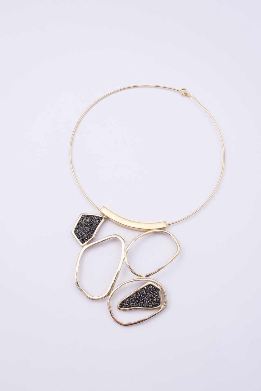 Glow Necklace angle view: handmade brass sculptural necklace with curved brass bar and cascading loops