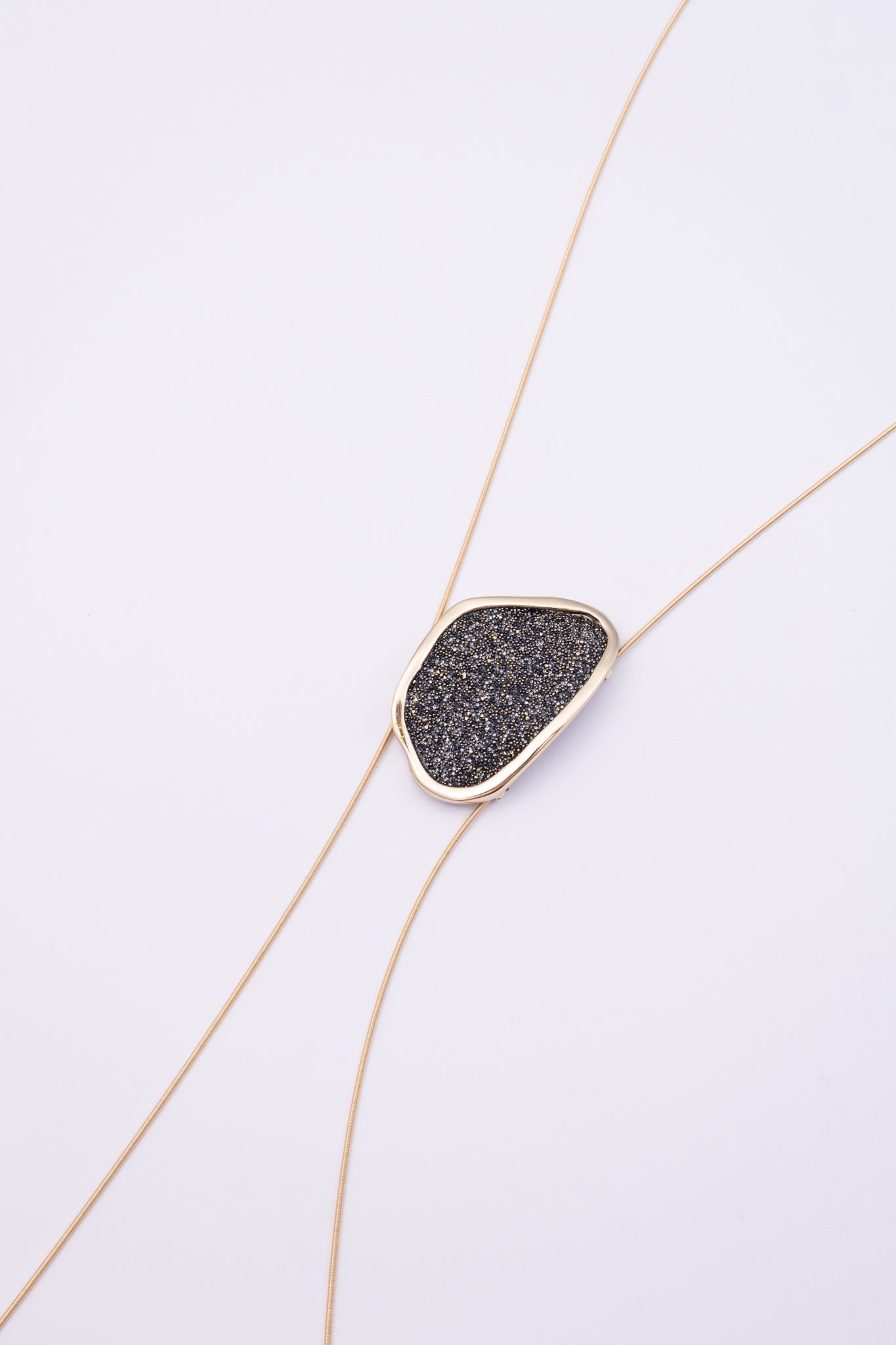 Shimmer Long Necklace close up: handmade brass pendant with tiny faceted crystals in a sleek organic brass frame