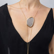 Shimmer Long Necklace worn on model: handmade brass long necklace with oval crystal pendant and slim coiled cords
