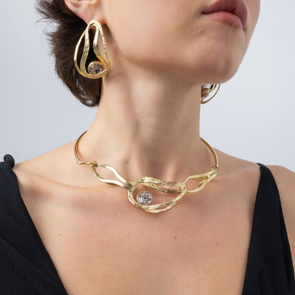 Model wearing the Boteh gold-plated brass collar necklace with a large clear crystal and matching paisley-inspired earrings, Savage Flora