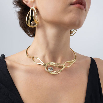 Model wearing the Boteh gold-plated brass collar necklace with a large clear crystal and matching paisley-inspired earrings, Savage Flora