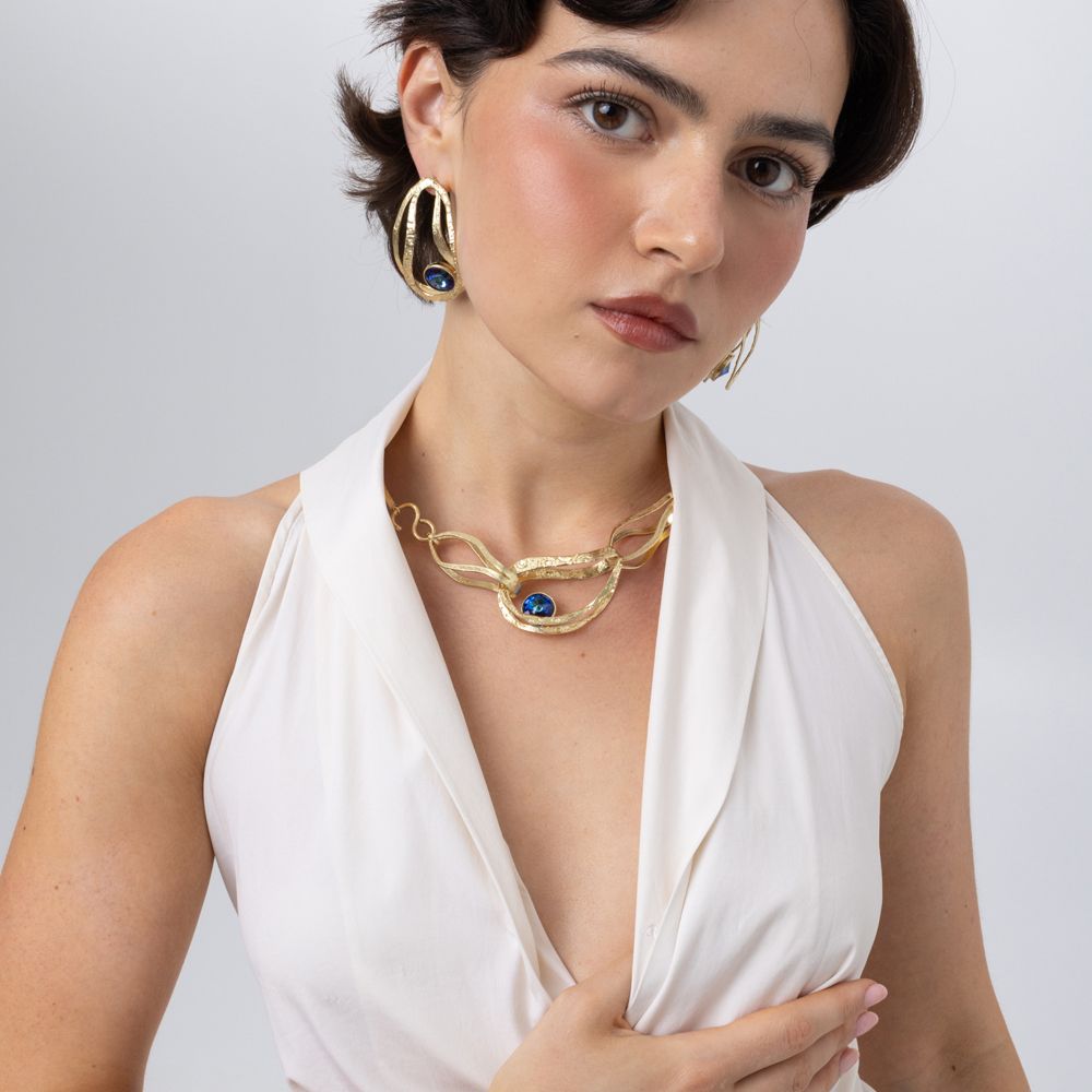 Model wearing the Boteh gold paisley statement necklace with iridescent blue crystal and matching earrings, Savage Flora