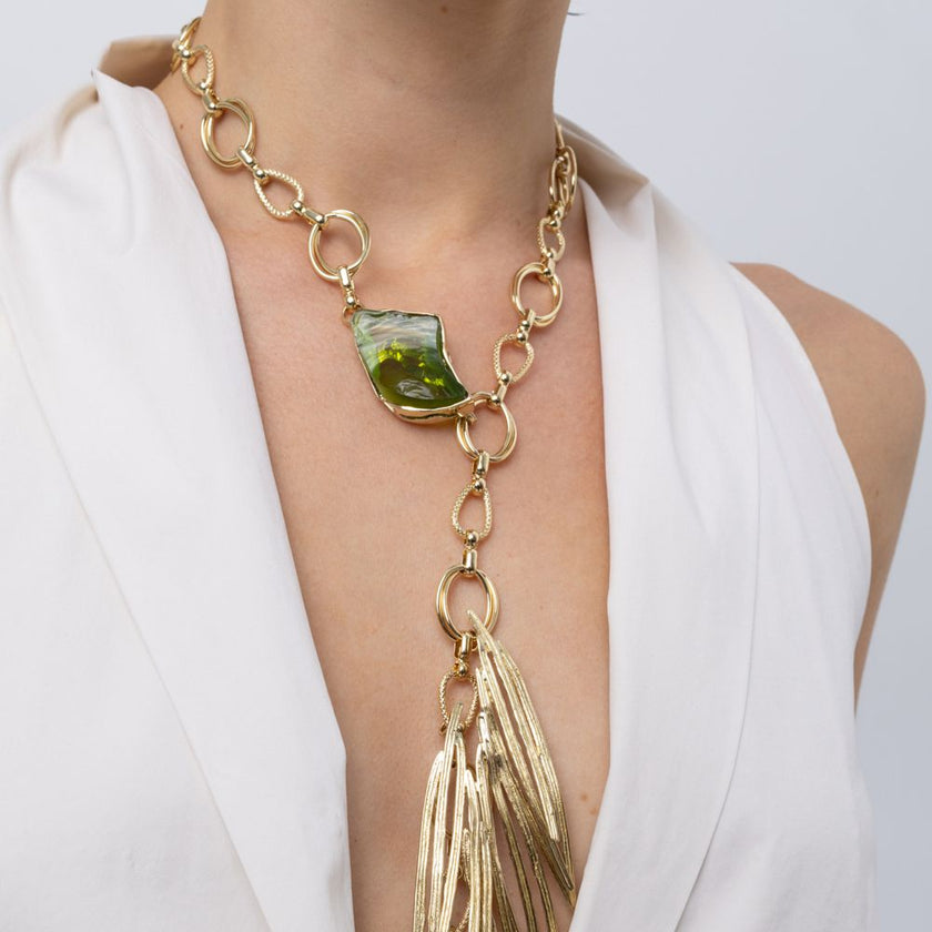 Woman wearing the Kite gold-plated Y-necklace with chunky chain, olive green resin stone and needle-like pendant, Savage Flora