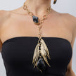 Woman wearing the Kite gold-plated chain necklace with black resin stones and long pendant of sculpted gold blades, Savage Flora