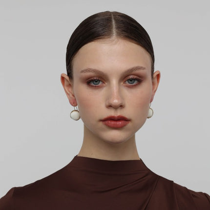 Kiss Earrings — handmade brass hook earrings with round resin stone pendant on model