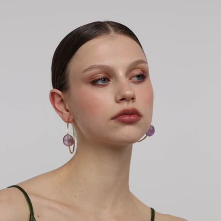 Kiss Hoop Earrings close-up — handmade brass setting holding a smooth raw resin stone at hoop base
