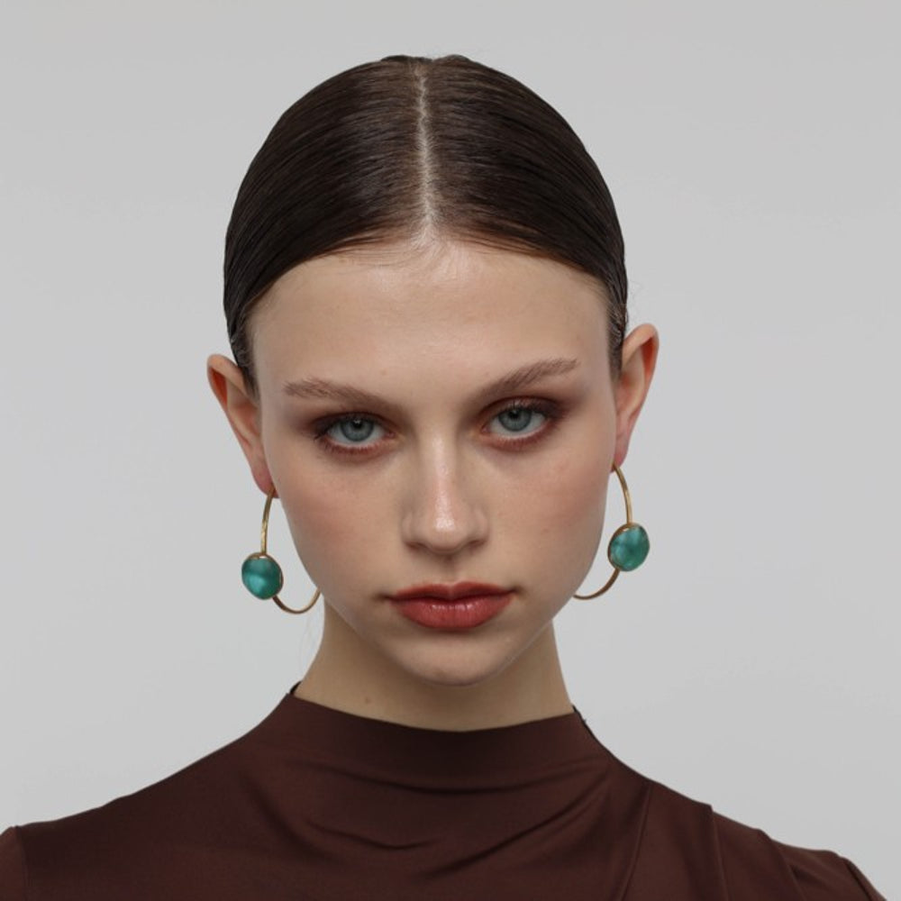 Kiss Hoop Earrings on model — handmade brass hoop earrings worn on ear showing scale and drape