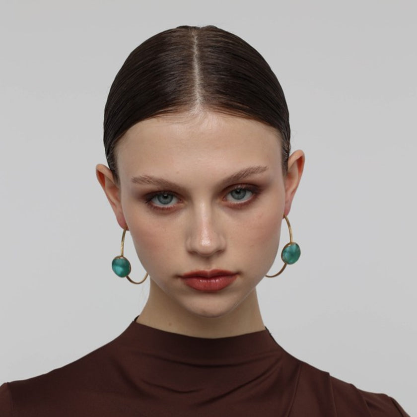 Kiss Hoop Earrings on model — handmade brass hoop earrings worn on ear showing scale and drape