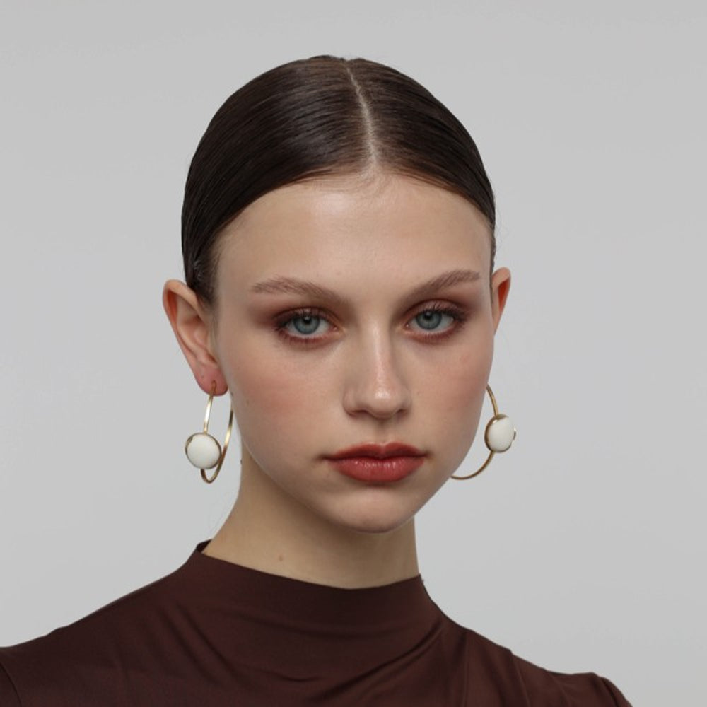 Kiss Hoop Earrings — handmade brass hoop earrings with round resin stone accent on model