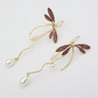 Dragonfly-shaped earrings with pearl accents on a light background