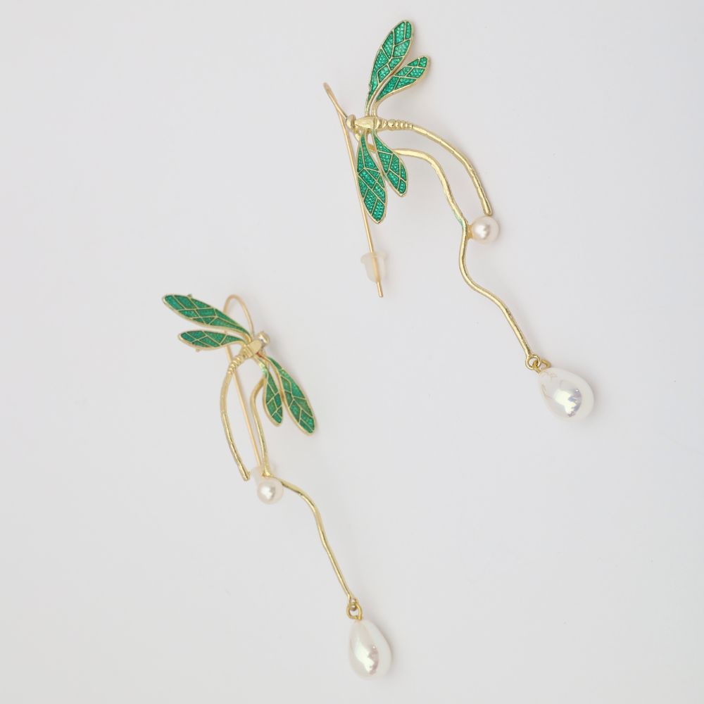 Gold earrings with green leaves and pearl drops on a light gray background