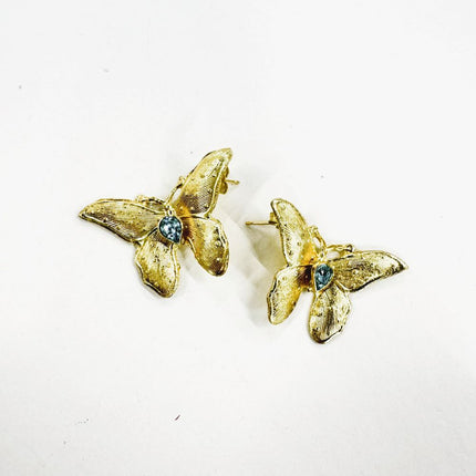 handmade brass butterfly earrings with blue crystal center stone, flat lay pair view