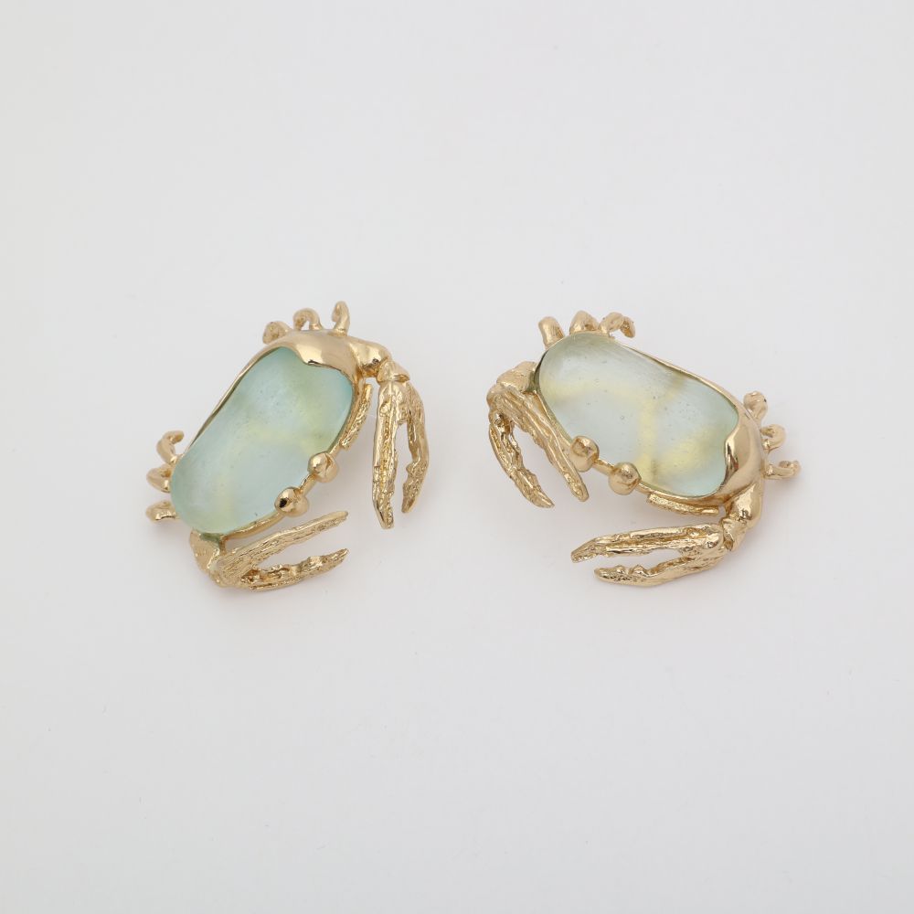 Pair of crab-shaped earrings with gold detailing on a light gray background