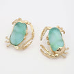 Gold earrings with green gemstones on a white background