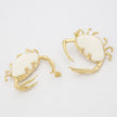 Pair of crab-shaped earrings with gold and white details on a light gray background