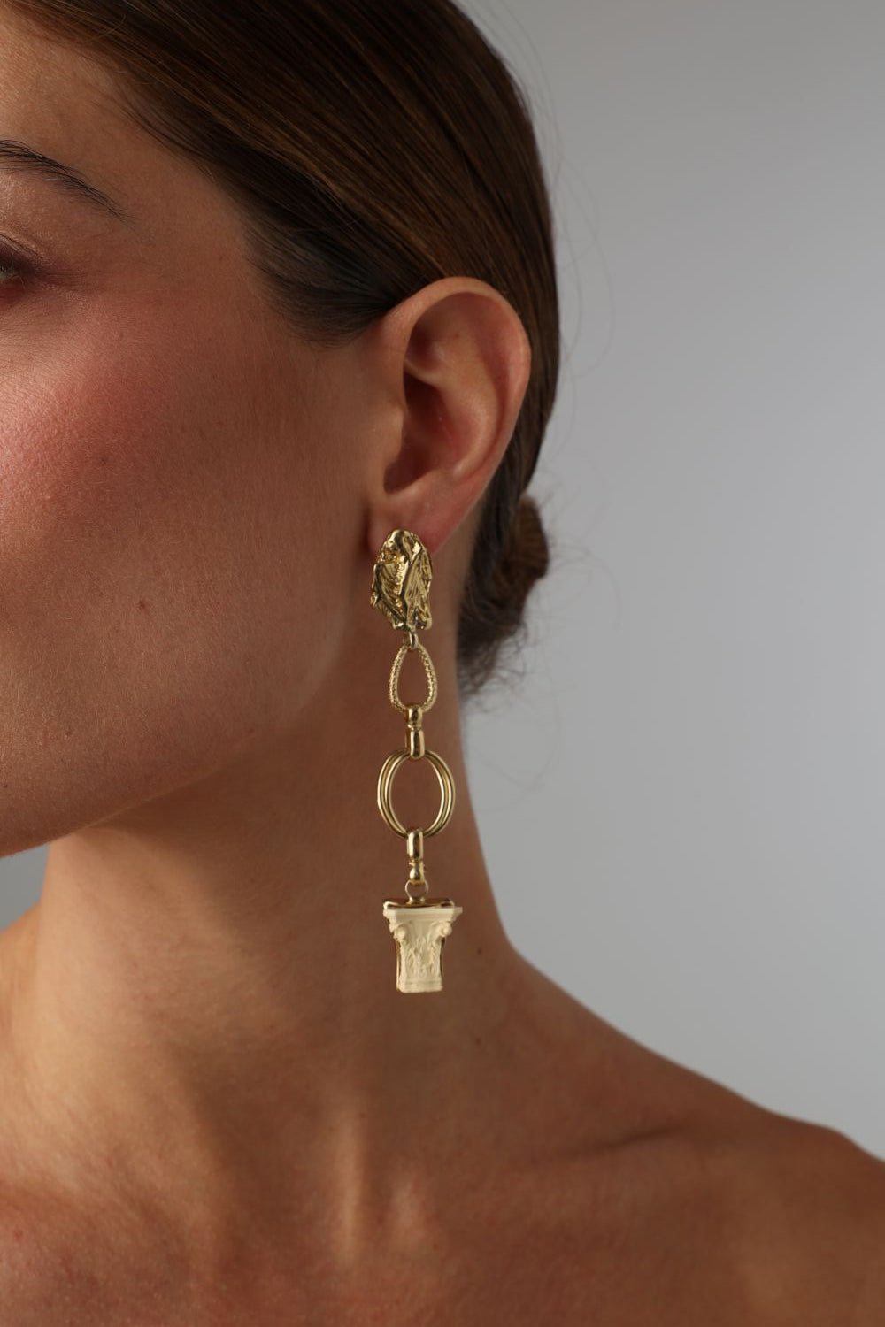handmade brass chain drop earrings with Greek column capital pendant on model, artisan jewelry made in Greece