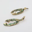 Pair of gold and green claw-shaped earrings on a light gray background