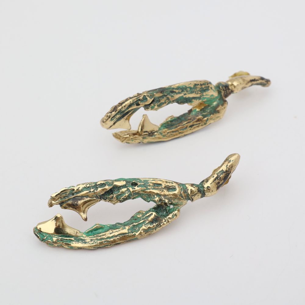 Pair of gold and green claw-shaped earrings on a light gray background