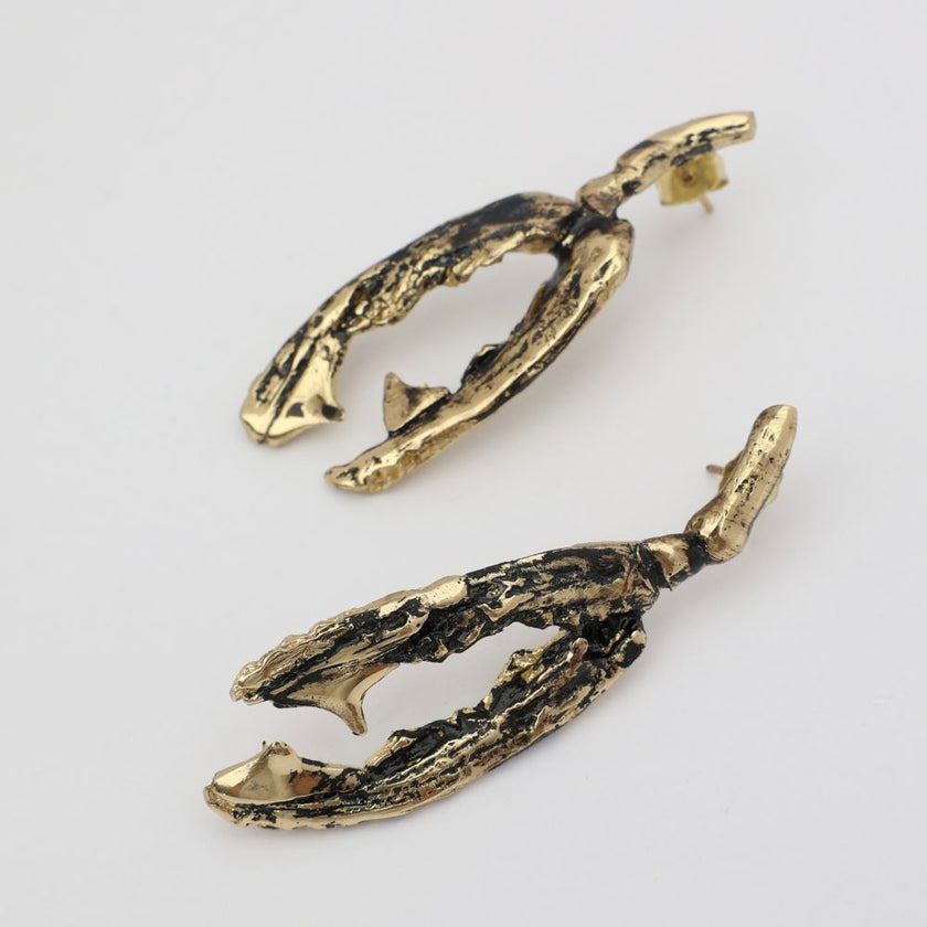 Pair of gold and black textured earrings on a light gray background