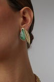 Handmade brass sculptural stud earrings with resin stone and leaf motif worn on model
