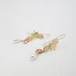 Pair of handmade bronze butterfly earrings with pink crystals and pearls on a white background.