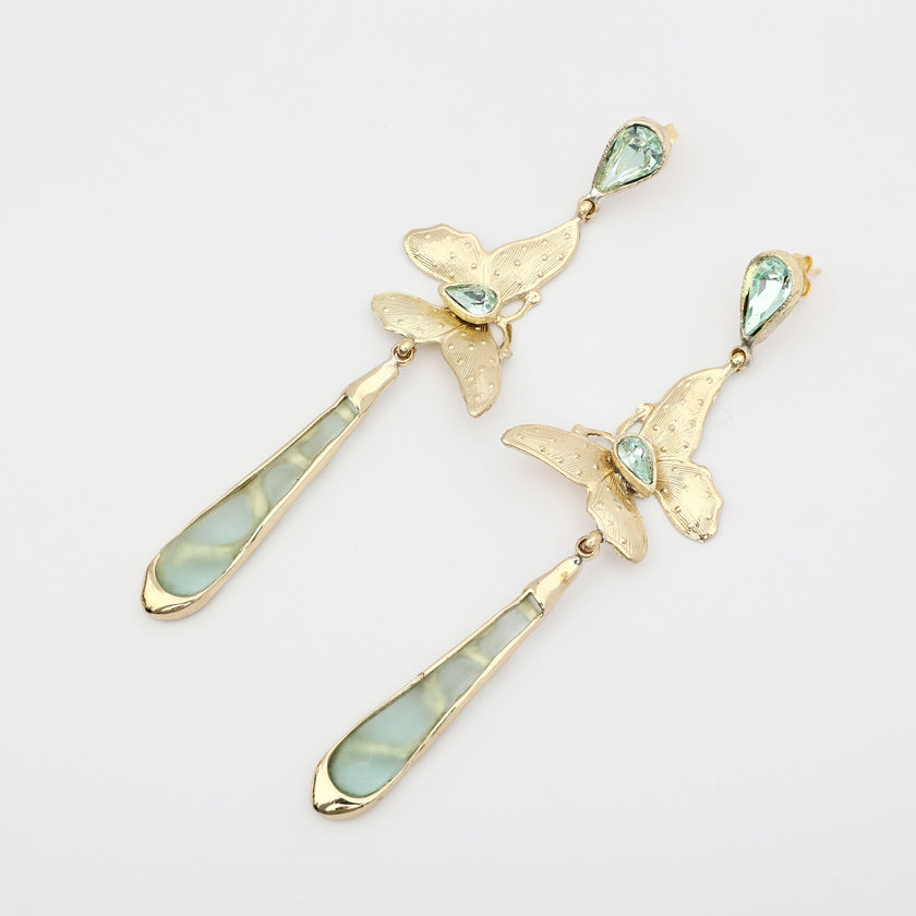 Pair of handmade bronze butterfly earrings with green crystals and long green drops on a white background.
